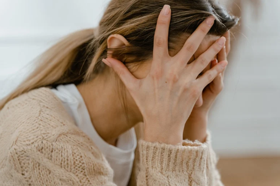Woman with head in hands, expressing emotional overwhelm, pain and chronic stress