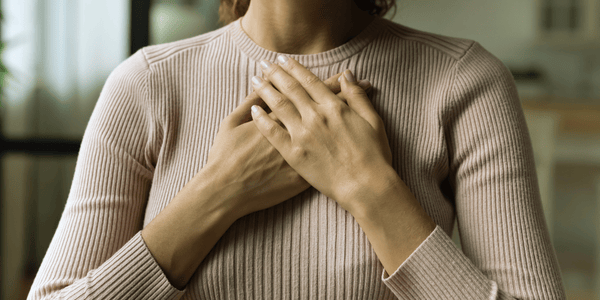 Woman with hands on her heart practicing somatic grounding to regulate the nervous system