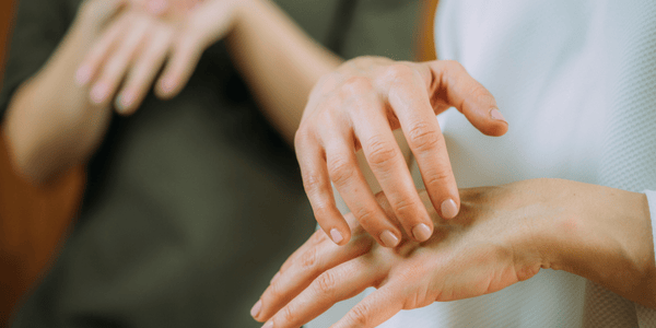 Close-up of hands guiding someone through EFT tapping for emotional release and pain relief